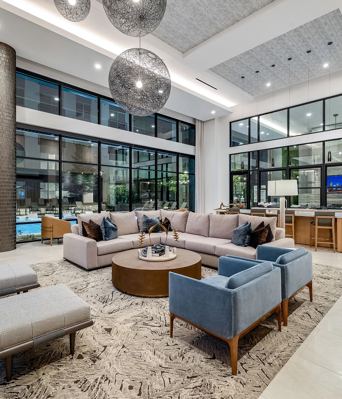 Luxurious apartment lobby showcasing elegant lounge area with plush seating, modern decor, and expansive windows overlooking a serene pool. Perfect blend of comfort and style.