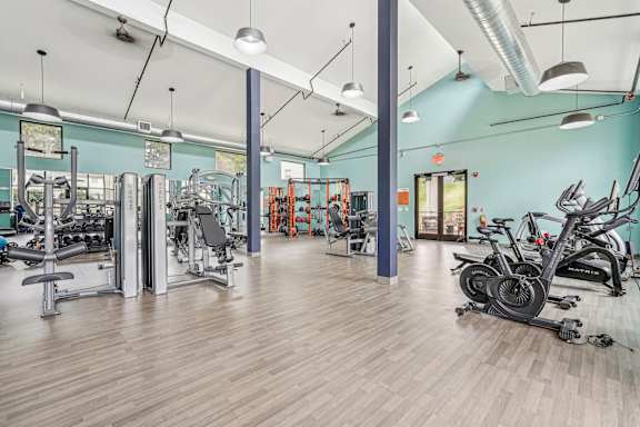 A gym with a variety of equipment including treadmills, weights, and exercise machines.