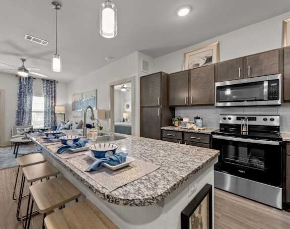 an open kitchen and dining area with a granite counter top and stainless steel appliances