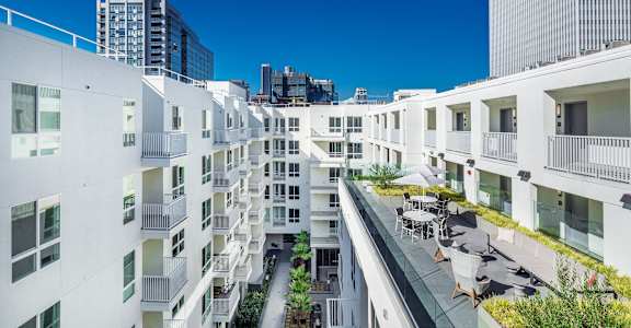 A white residential building with balconies and a small garden in the courtyard. at G12 Apartments, Los Angeles, CA, 90015