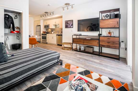 A modern bedroom with a bed, a desk, and a shelf at G12 Apartments, Los Angeles, 90015