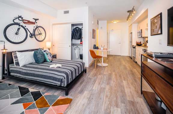 A bedroom with a bed, a chair, and a bicycle on the wall at G12 Apartments, Los Angeles, CA