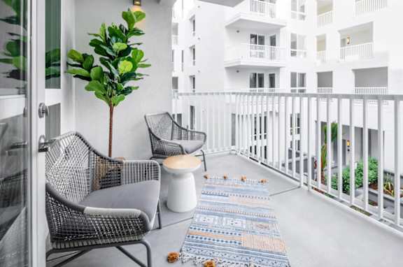 A balcony with a chair, table, and potted plant at G12 Apartments, CA, 90015