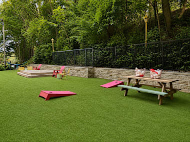A playground with a green surface and a picnic table.