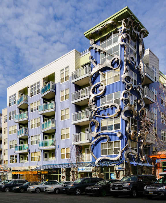 A modern building with a blue and white design is surrounded by cars.