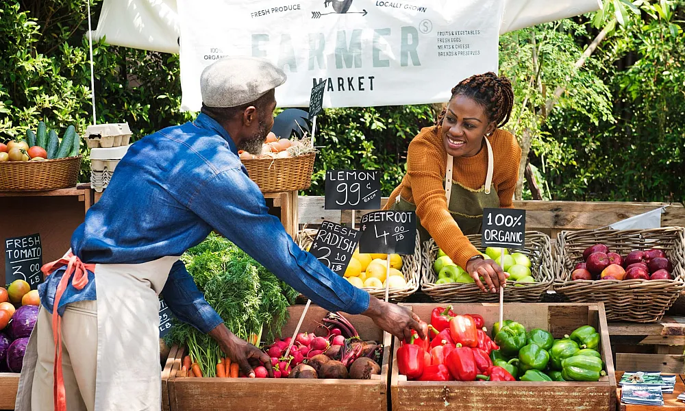 man and woman working farmers market booth