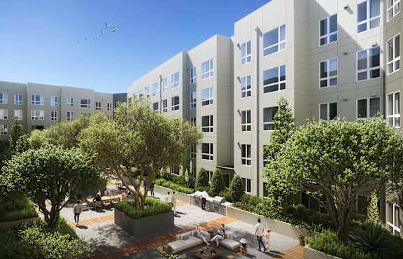 A courtyard with a fountain and people sitting on benches is surrounded by apartment buildings.