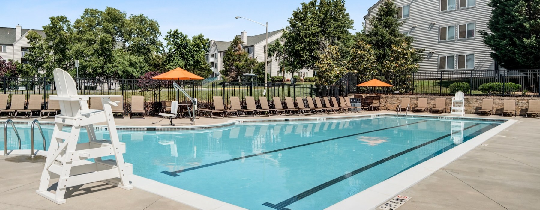a swimming pool with chairs and umbrellas by a house