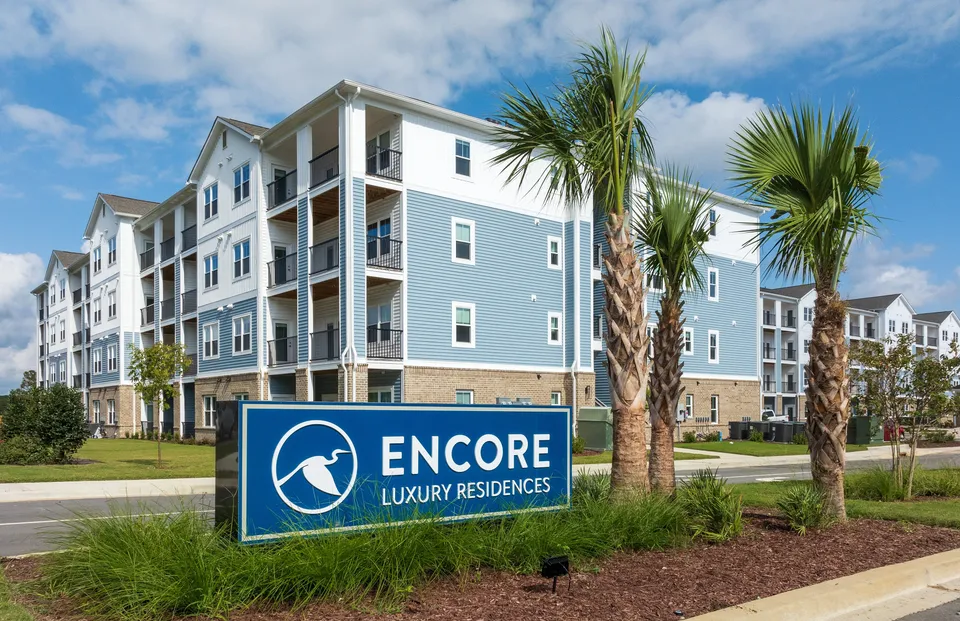 Modern apartment complex featuring stylish architecture and palm trees under a blue sky.