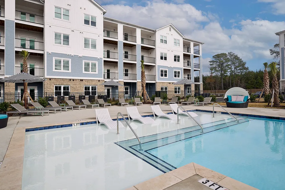 Modern apartment complex with a luxurious pool and stylish lounge area.