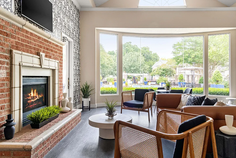 Inviting living room with a cozy fireplace, modern decor, and expansive windows showcasing a beautiful outdoor view.