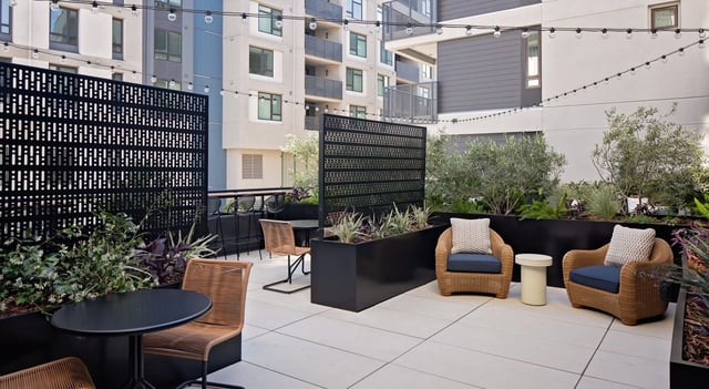 Outdoor lounge area with chairs, tables, and string lights.
