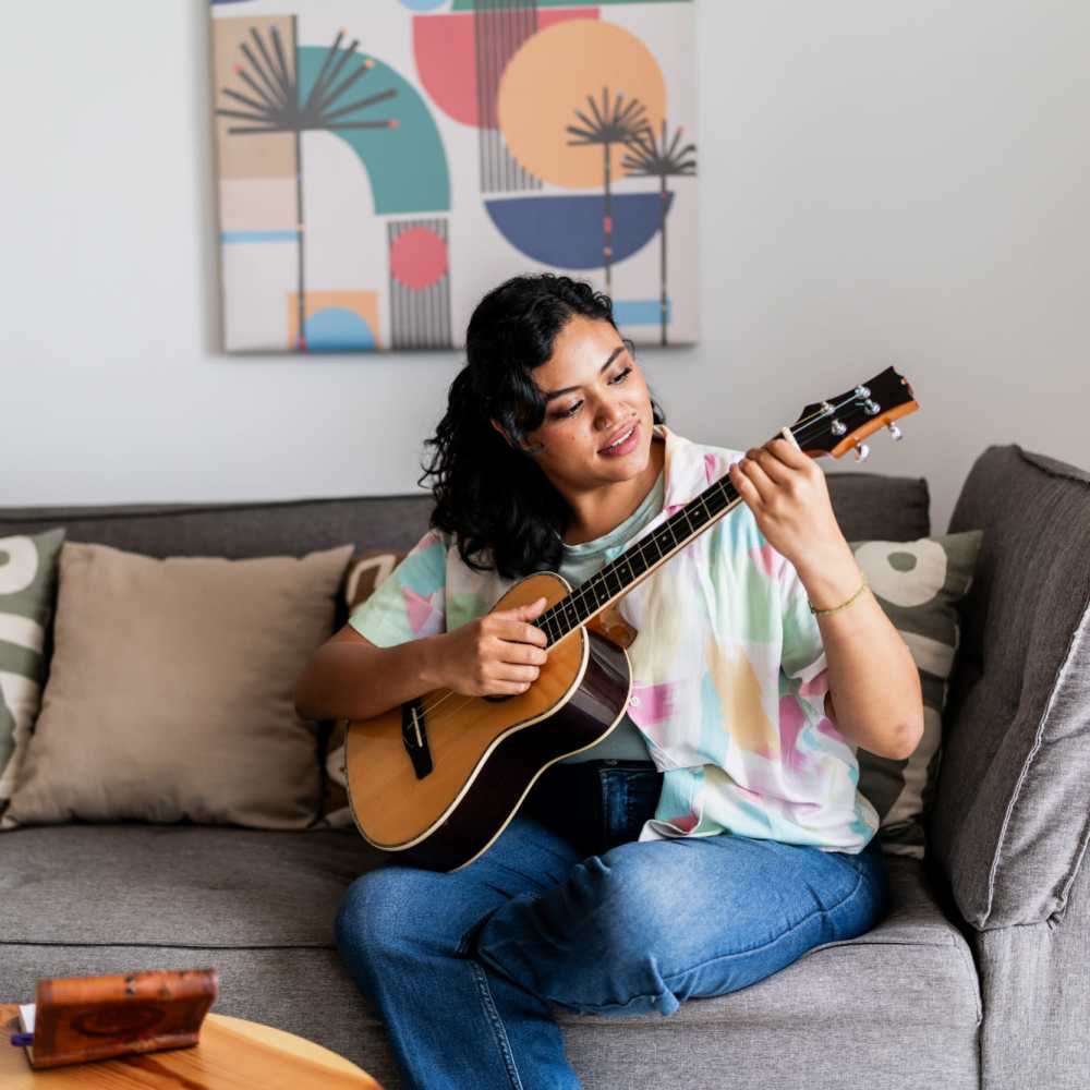 Resident playing guitar in a living room at Flatiron West Trade in Charlotte, North Carolina