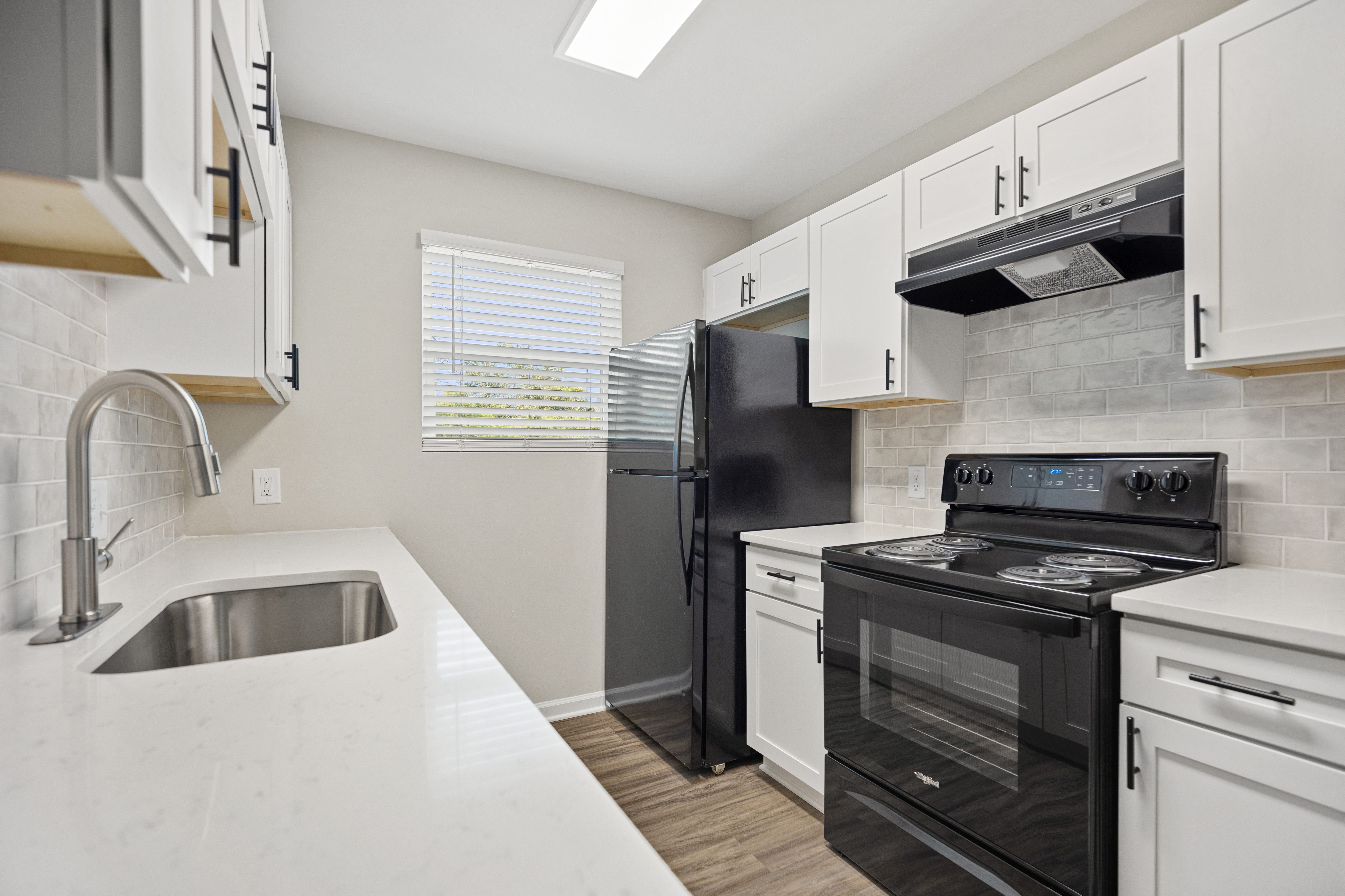 A kitchen with black appliances and white cabinets.