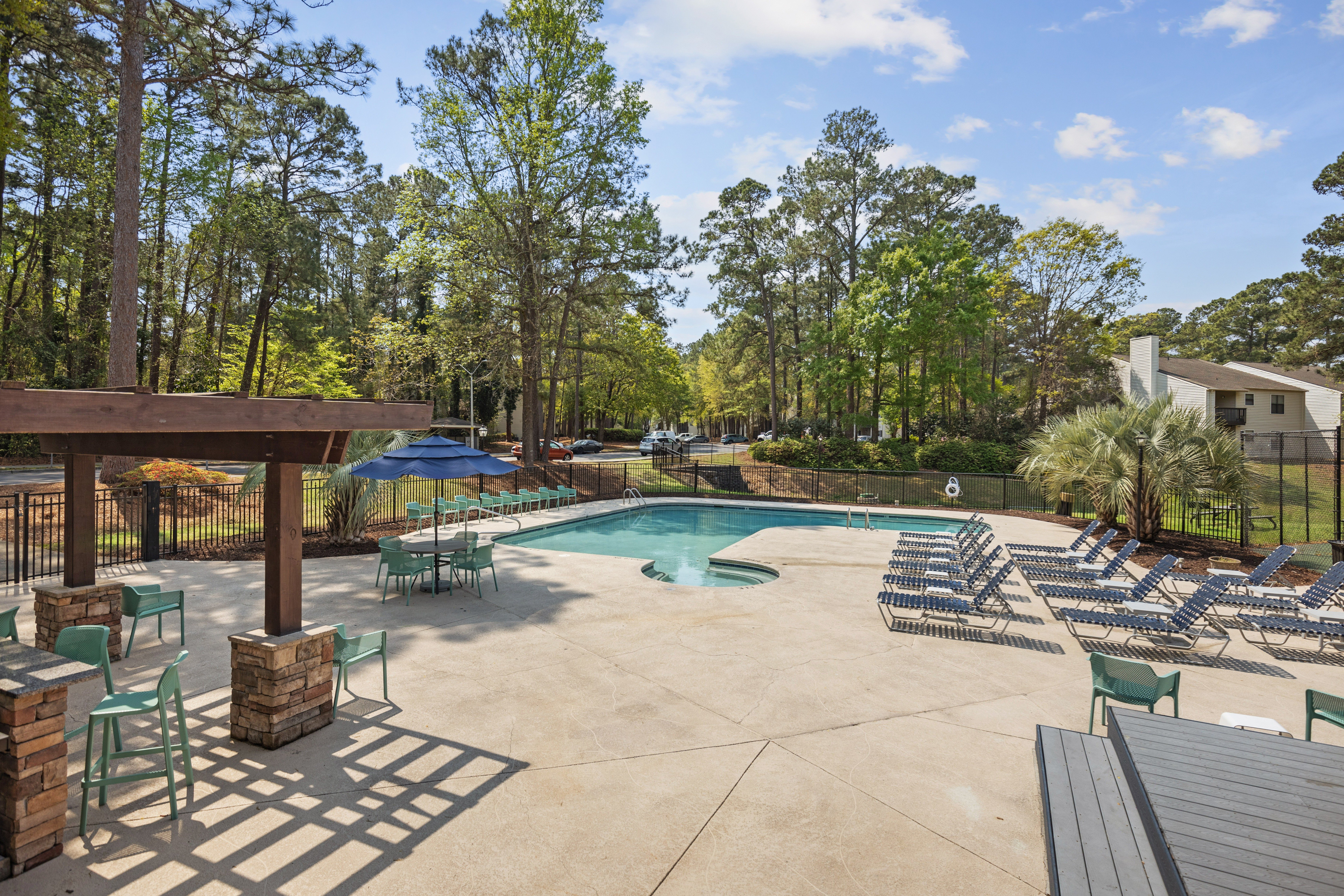 A pool surrounded by trees and chairs.