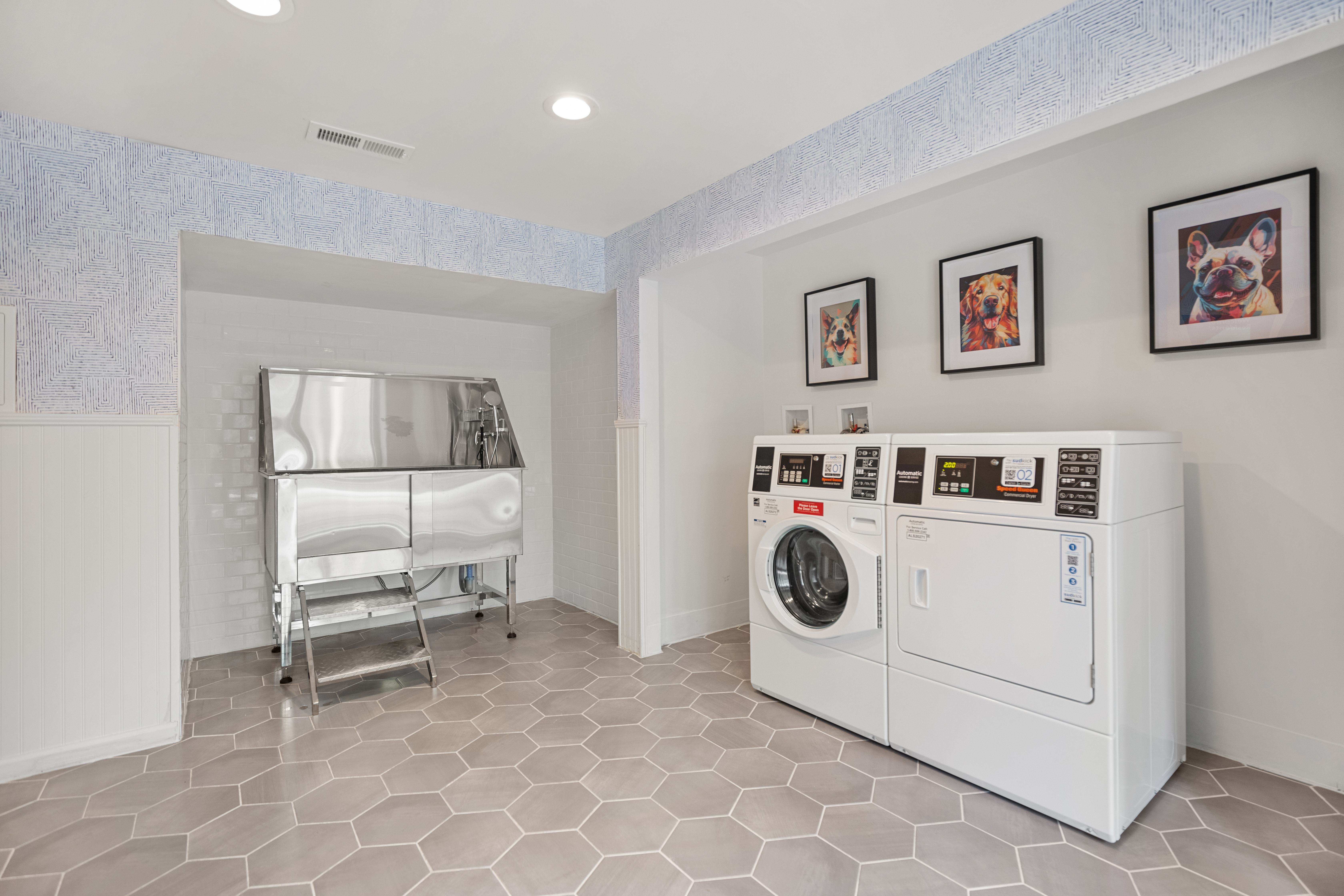 A laundry room with a washer and dryer and pictures on the wall.