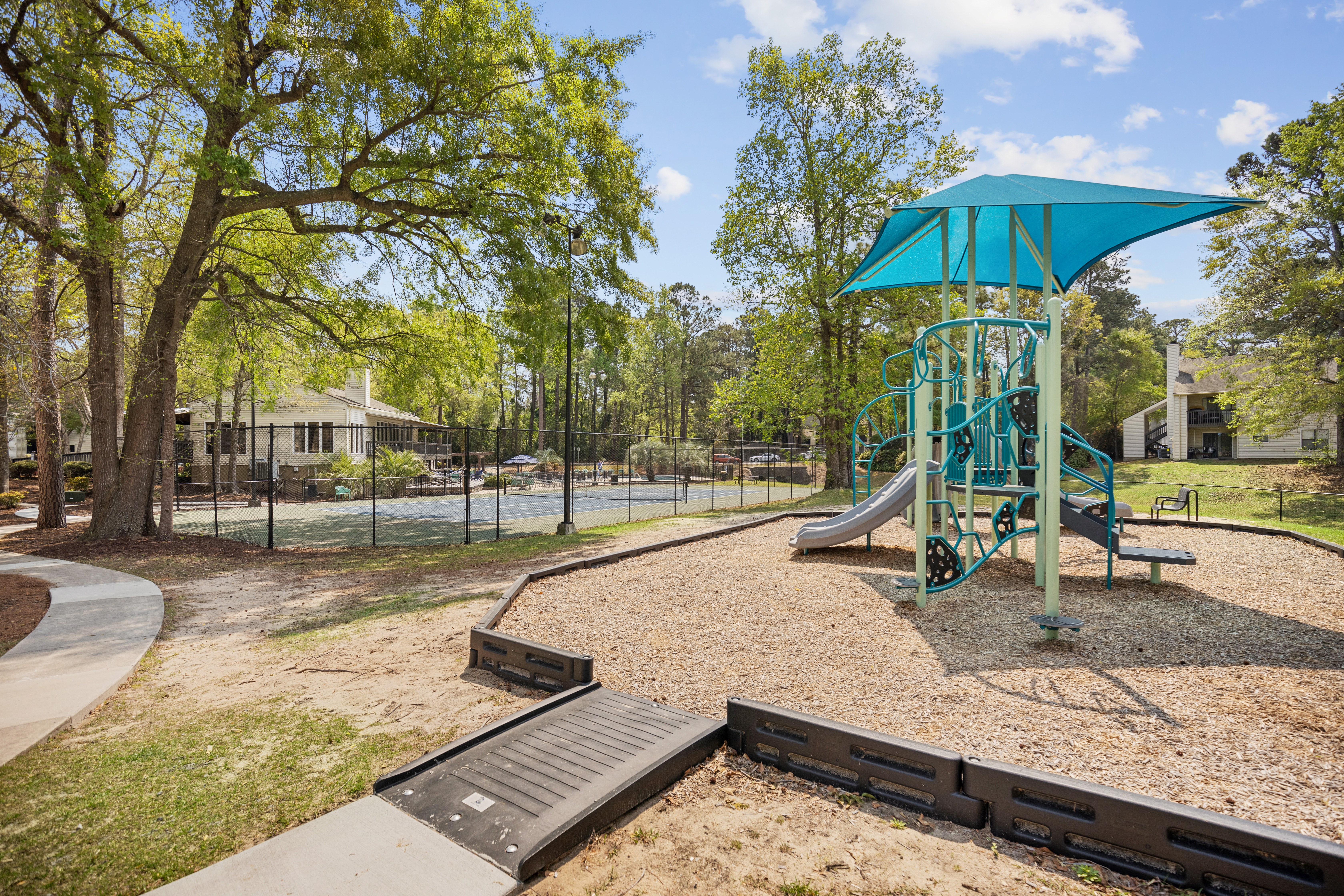 A playground with a blue umbrella and slide.