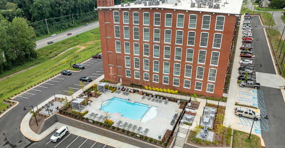 A large red brick building with a pool in front.