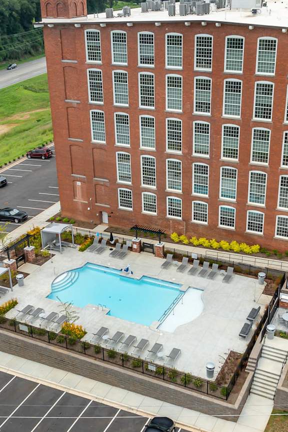 A large red brick building with a pool in front.