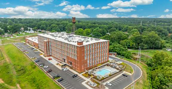 A large red brick building with a pool in front of it.