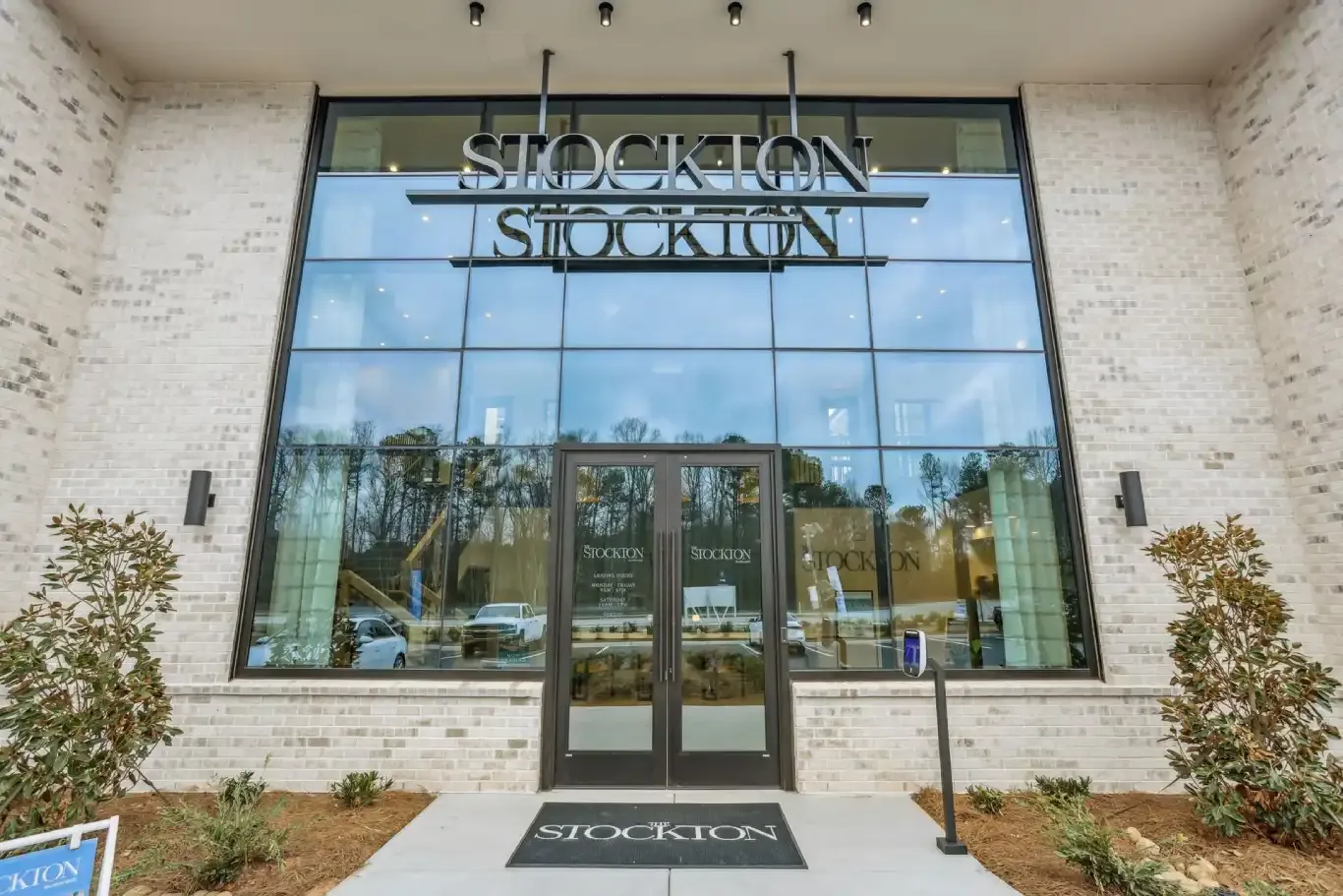The Stockton building entrance features a large glass facade, dark-framed double doors, and white brick walls.