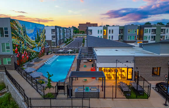 A sunset view of a pool area with a mural on the side of a building.