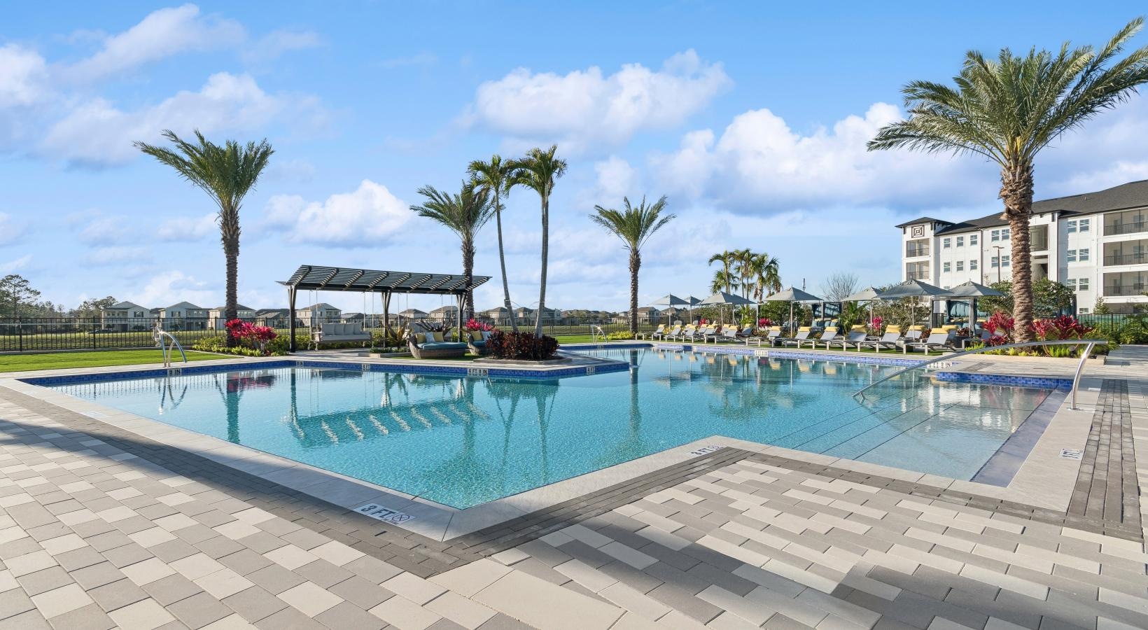 a pool with palm trees and building in the background