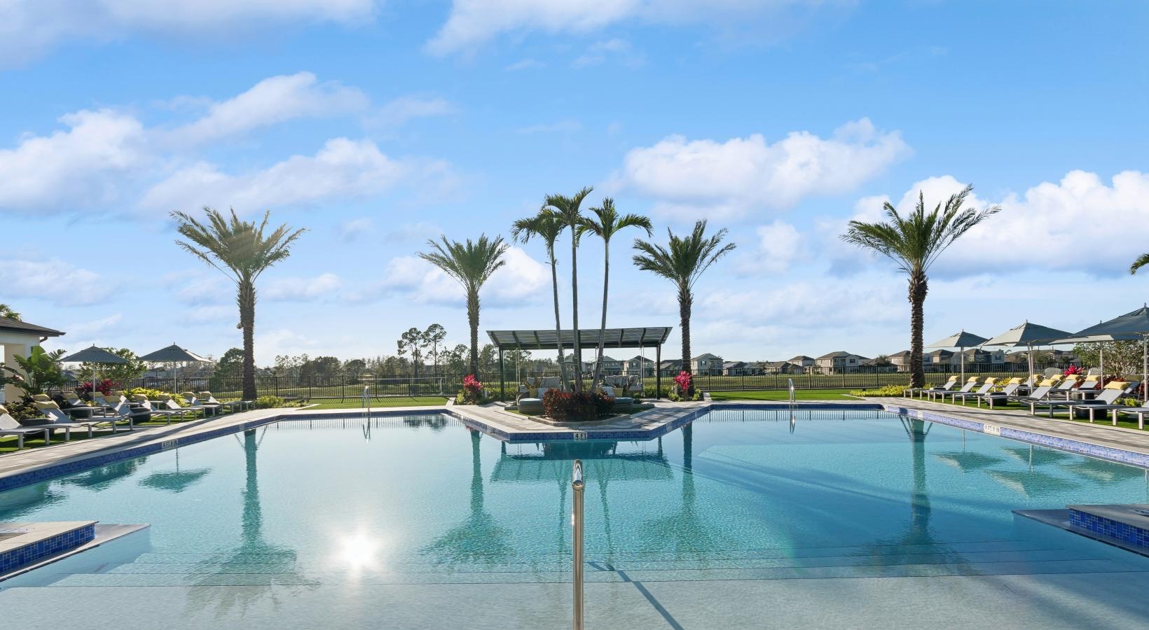 a pool with palm trees and a building in the background