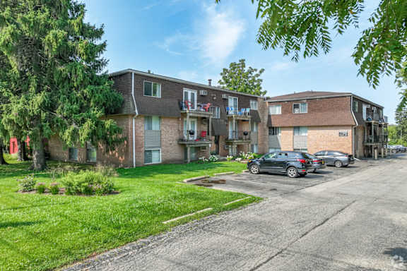 A row of houses with cars parked in front.
