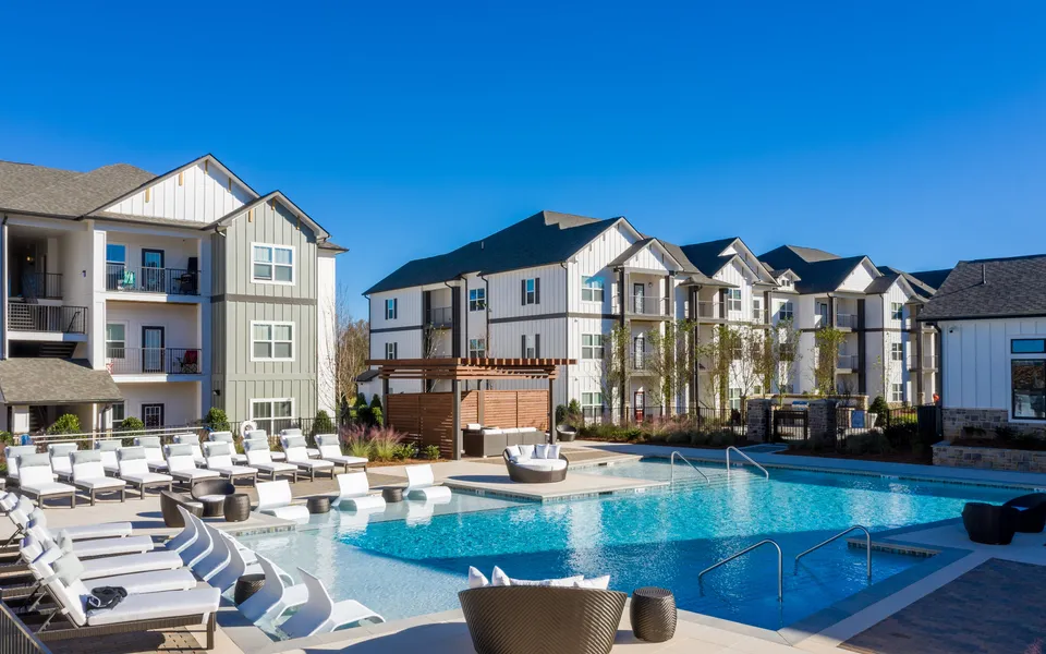 Charming apartment complex featuring stylish buildings surrounding a crystal-clear swimming pool with modern lounge chairs.