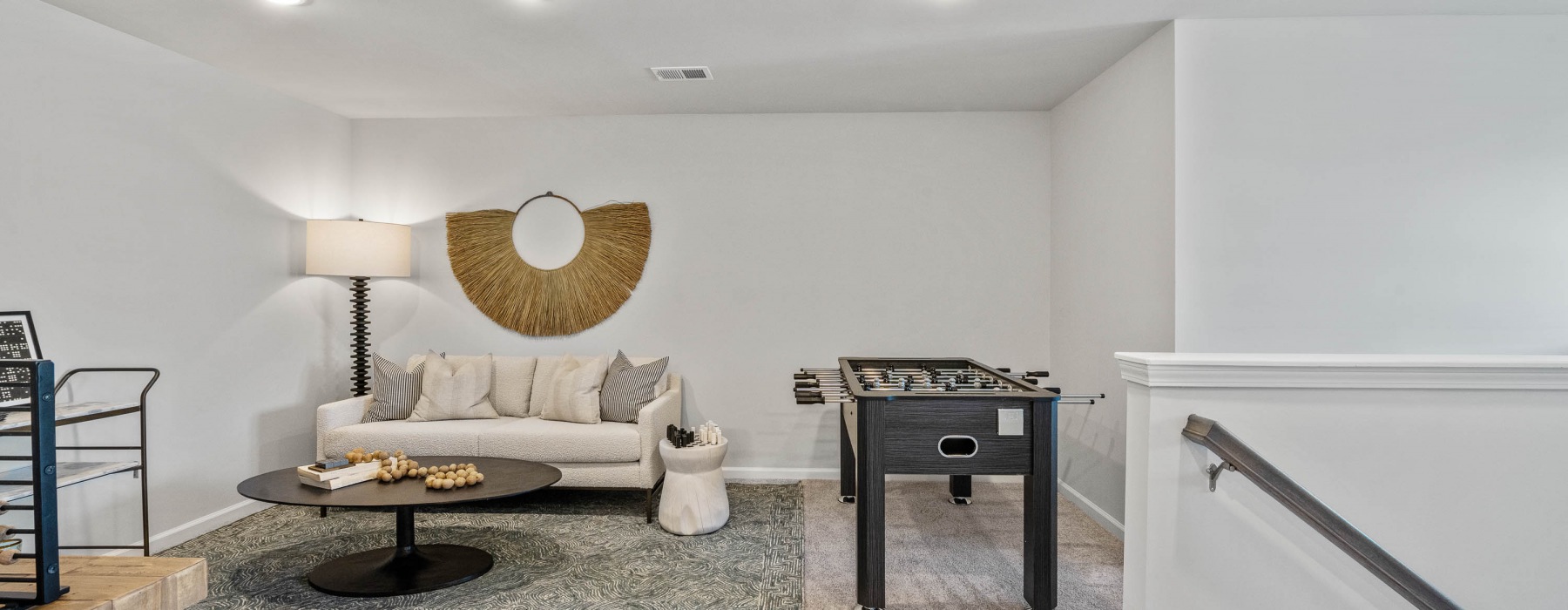 Spacious and well lit living room with wood floors and a large window with access to the kitchen
