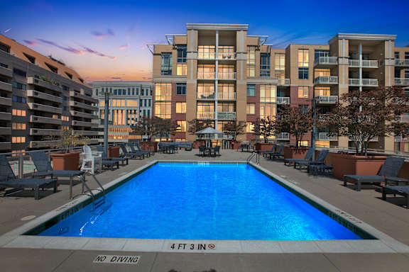 A large swimming pool in front of apartment buildings with a "No Diving" sign.