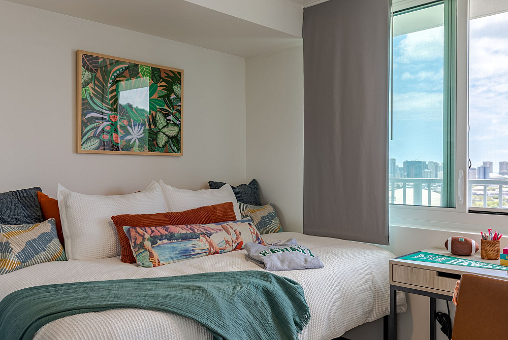 Bright and modern bedroom with cozy bed, vibrant pillows, and a large window offering a stunning city view.