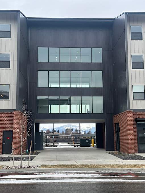 A modern building with a black and grey facade and a glass entrance.