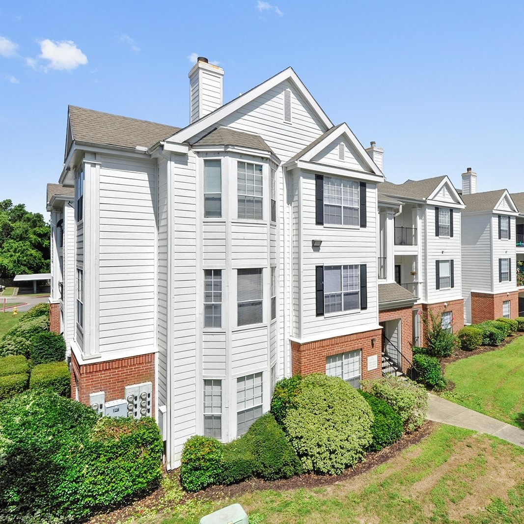 Exterior front view of the The Preserve Apartments in Gulfport MS showing white siding, black shutters and red brick with landscaping
