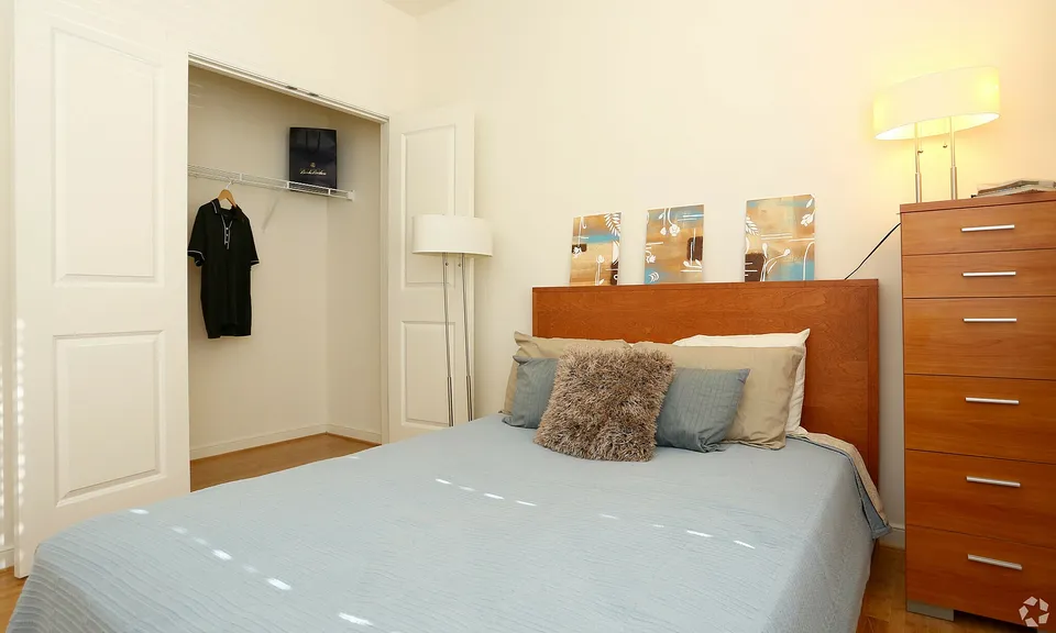 Inviting bedroom with soft blue bedding, a wooden headboard, and warm lighting.