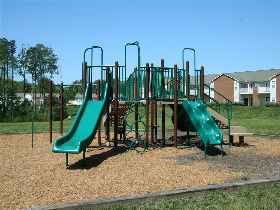 Inviting playground featuring slides and climbing structures amidst lush greenery.