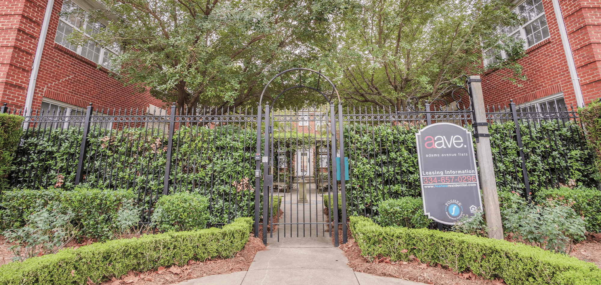 The gated courtyard entrance to Adams Avenue Flats with landscaping