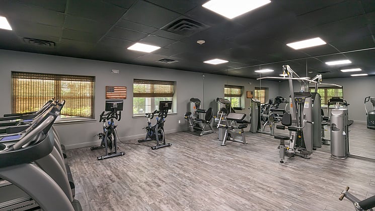 Modern fitness center with state-of-the-art equipment, including treadmills, stationary bikes, and strength machines. Spacious and well-lit with sleek flooring and large mirrors.
