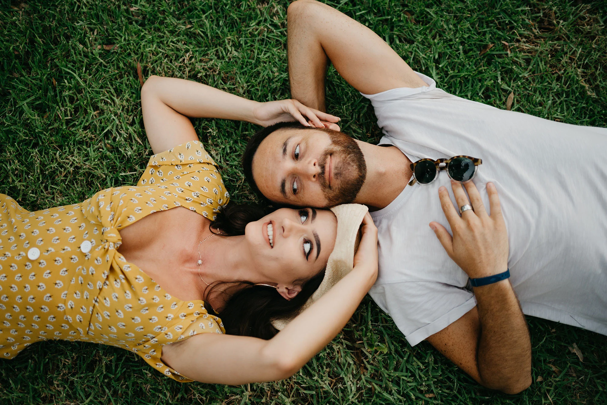 Top-down photo of a man and woman lying on the grass in the spring