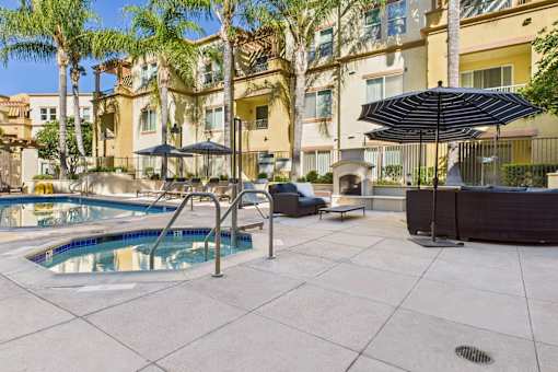 A pool area with a black umbrella and a blue pool.