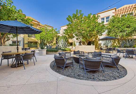 A patio with a table and chairs and umbrellas.