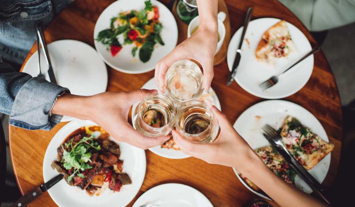 Friends having food and drinks at a restaurant near Pure Lowell Apartments in Lowell, Arkansas