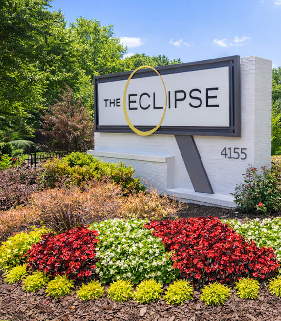 A sign for The Eclipse with a flower bed in front.