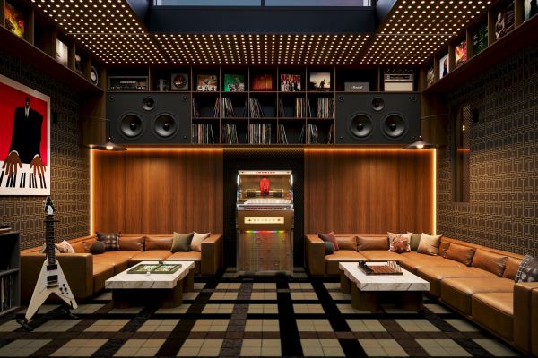 A stylish music-themed lounge with brown sofas, a jukebox, guitars, large speakers, records, and music posters.