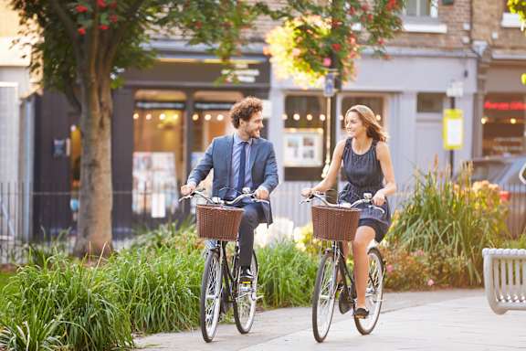 A man and a woman riding bicycles on a sidewalk.