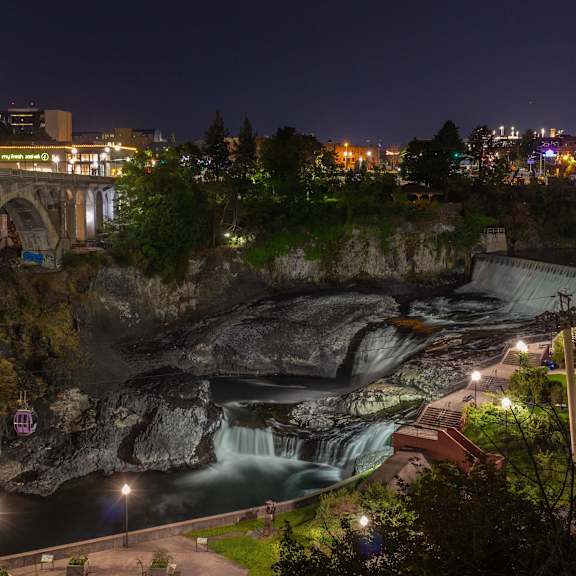 A waterfall cascades down a rocky cliff at night.