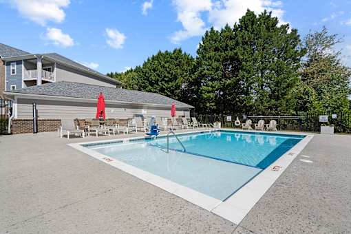 Resort-style swimming pool in Hickory, NC at Hawks Landing with umbrellas and fenced lounge area