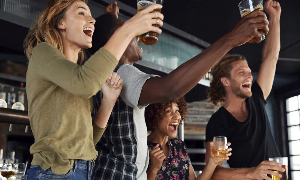 People at bar celebrating with drinks in their hand