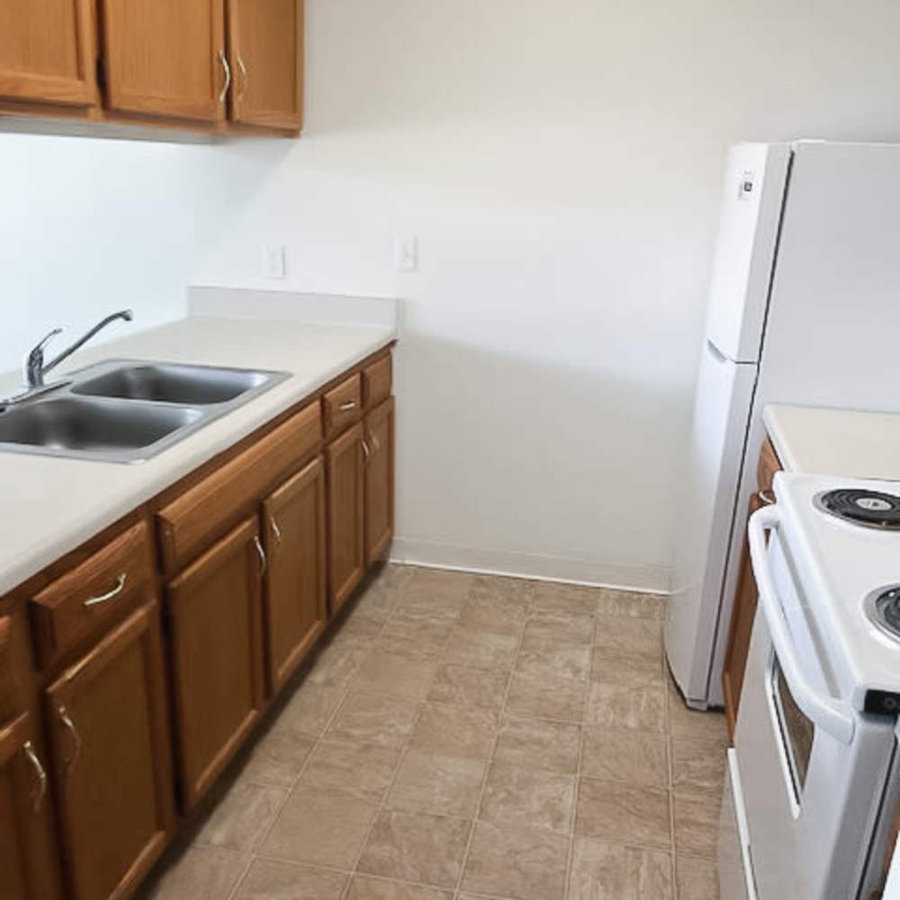 Apartment kitchen with tile flooring, cabinetry and refrigerator at Carriage Town Square in Flint, Michigan